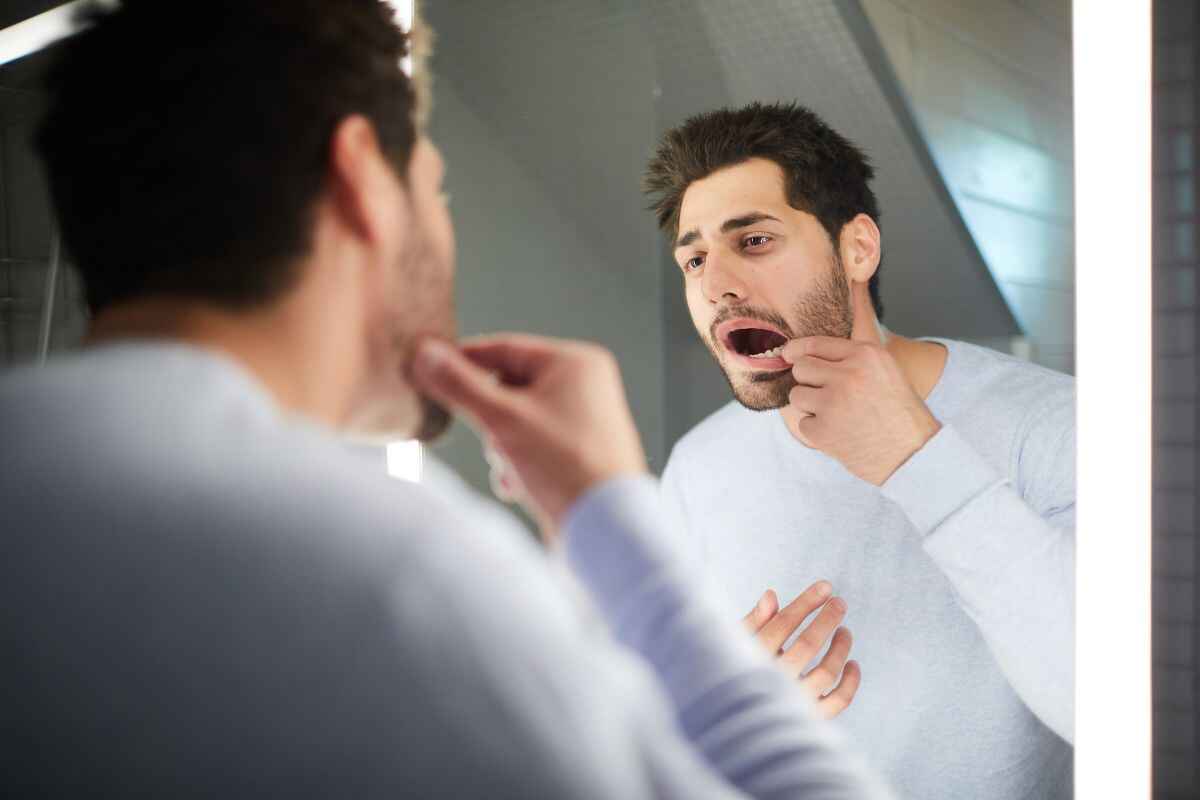 man checking in mirror how dental crown causing problems